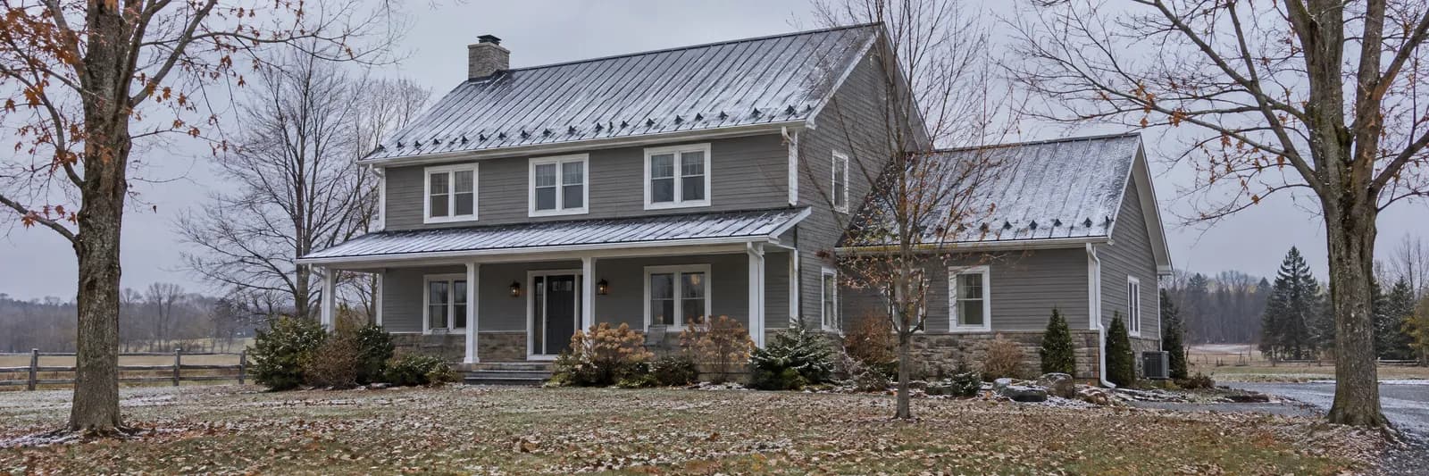 An Ontario country house with a metal roof under the first light snow