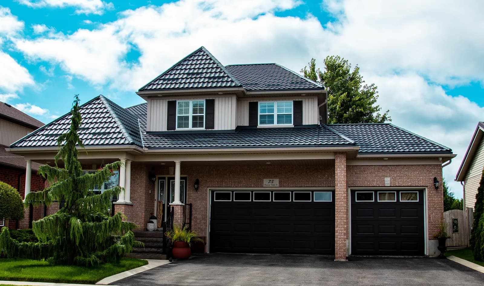 Black Tremblant metal tile roof on a two-storey brick house