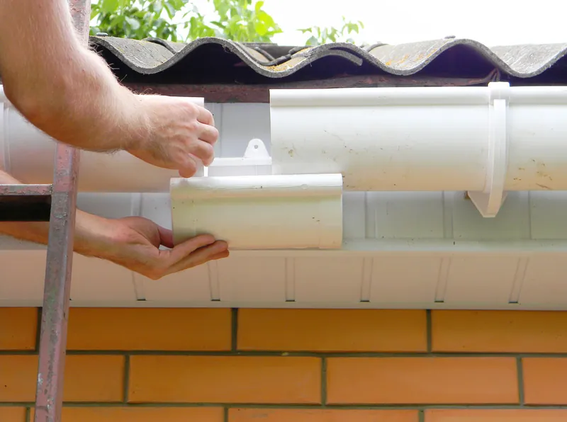 Close-up of a white eavestrough and its joint at the roof edge
